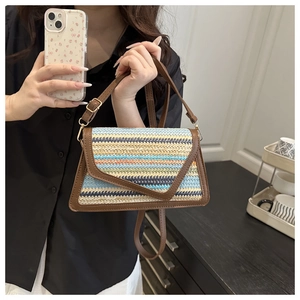 Detail of colorful woven straw handbag with adjustable strap and dark brown trim