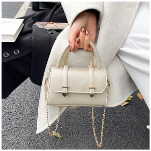 Détail du sac beige en cuir Saffiano avec bandoulière chaîne dorée et clous décoratifs