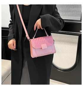Detail of pink crossbody bag with crocodile texture flap and gold hardware accents