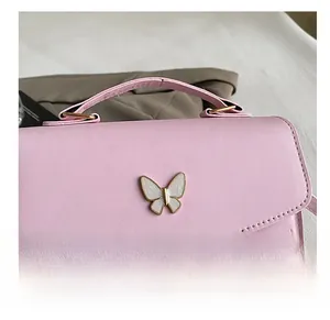 Gros plan sur le sac à main rose avec logo papillon blanc et coutures en chevron