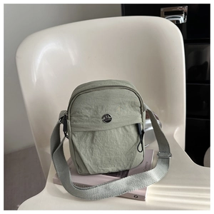 Detail of light green nylon shoulder bag with adjustable strap and metal logo