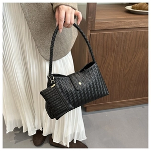 Detail of black woven underarm bag with matching coin purse and metallic magnetic closure
