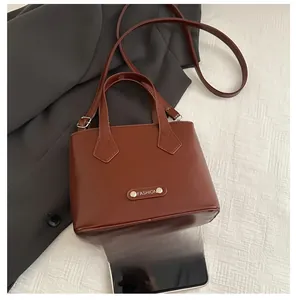 Close-up of caramel brown bucket bag with adjustable strap and metal fashion plaque