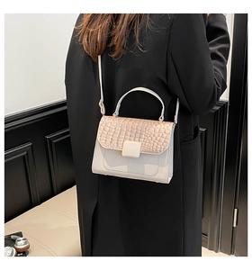 Detail view of cream crossbody bag with crocodile texture flap on model's shoulder