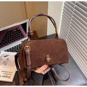 Close-up of brown suede bag texture with golden twist lock and dark leather handle