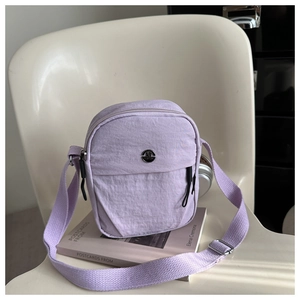 Detail of light purple nylon crossbody bag with adjustable strap and metal logo plaque
