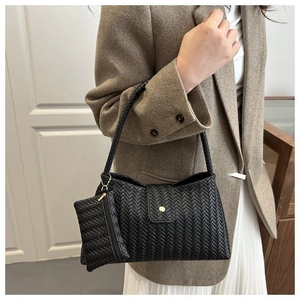 Detail of black woven shoulder bag with matching mini pouch on a stylish female model