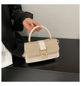 Detailed view of luxury cream handbag featuring sequin flap and gold D-ring buckle