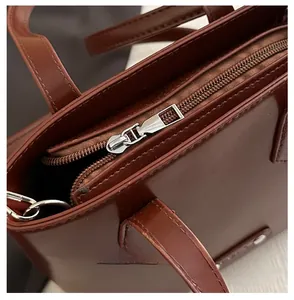 Detail view of smooth silver metal zipper and brown leather texture on bucket bag