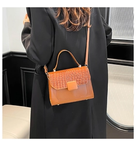 Rear view of model wearing a brown crossbody bag with crocodile texture flap detail