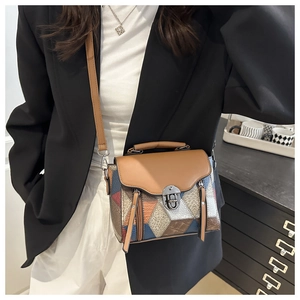 Macro detail of geometric color block patchwork and metal twist lock on shoulder bag
