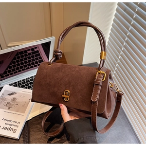 Detail of dark brown suede and leather stitching with a gold twist lock on handbag