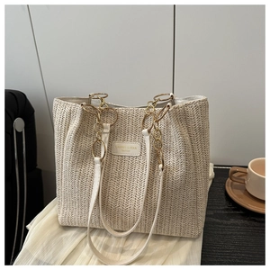 Detailed texture of woven straw tote bag with elegant white leather strap and gold chain