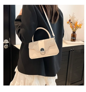 Detailed view of a creamy white hardshell box bag with metallic texture and hand strap