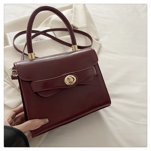 Detailed close-up of dark red square handbag featuring a golden bead turn-lock buckle