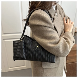 Detail of black woven leather shoulder bag with matching mini zipper pouch on model