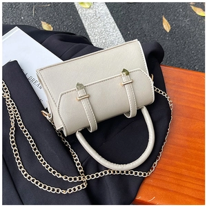 Détail du sac mini en cuir Saffiano beige avec chaîne dorée sur surface en bois