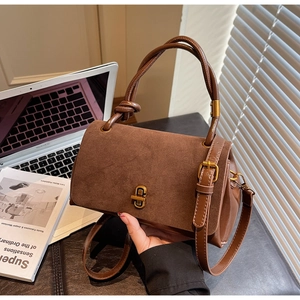 Detail of brown suede tote bag with golden twist-lock and unique knotted handle design