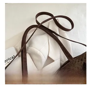 Dettaglio di una borsa tote in maglia marrone con motivi traforati e manici in ecopelle