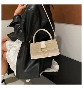 Detail of cream leather handbag with gold sequin flap and metallic U-shaped buckle
