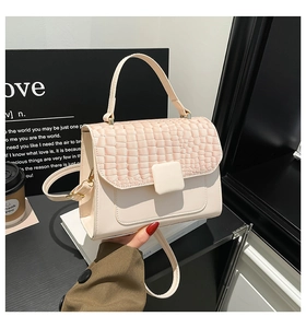 Detail of cream white leather bag with flap crocodile pattern and gold square buckle
