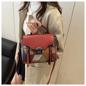 Detail of color-block tote bag featuring red flap with long tassel and crossbody strap