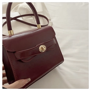Close-up of wine red leather handbag with golden twist lock and round handle