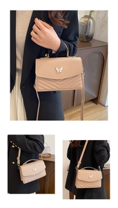 Détail du sac bandoulière beige avec boucle papillon et coutures matelassées en V