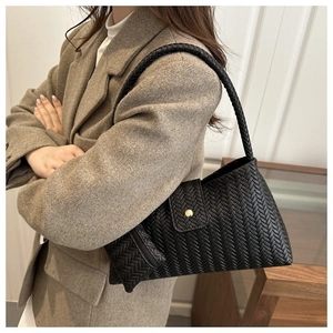 Detail of black woven shoulder bag with small coin purse and elegant gold buckle