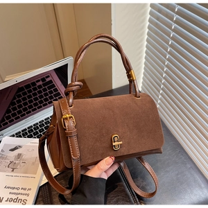 Detail of suede and smooth leather handbag with gold twist lock and woven handle