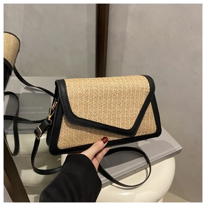 Detailed view of women's woven straw crossbody bag with black leather trim and gold buckle
