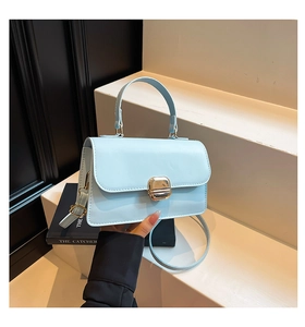 Detail of light blue crossbody bag featuring a golden square twist-lock and slim strap