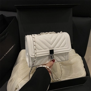 White quilted crossbody bag with silver chain strap and metal lock in a gift box