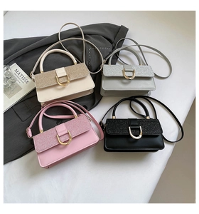 Close-up of four glitter and leather crossbody mini square bags with gold D-buckles
