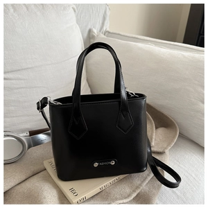 Minimalist black bucket bag with silver Fashion plaque on a cozy home setting