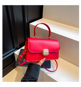 Close-up of vibrant red leather handbag featuring a square gold metal clasp lock