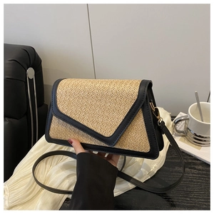 Detail of woven straw crossbody bag with black leather trim and V-shaped gold buckle