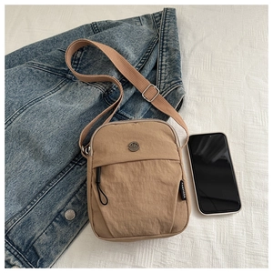 Detail of khaki nylon crossbody bag with metal M logo and adjustable fabric strap