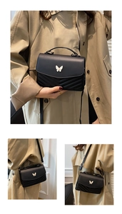 Détails du sac bandoulière noir avec boucle papillon blanche et surpiqûres en V