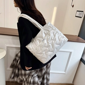Grand sac cabas matelassé argenté porté à l'épaule avec des détails de surpiqûres