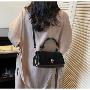 Detail of suede and leather patchwork handbag with gold metal lock and knotted handle