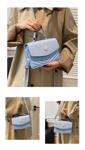 Détail du sac bandoulière bleu clair avec boucle papillon et surpiqûres en forme de V