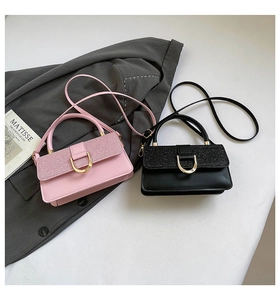Detail of pink and black leather bags featuring glitter texture and golden buckle