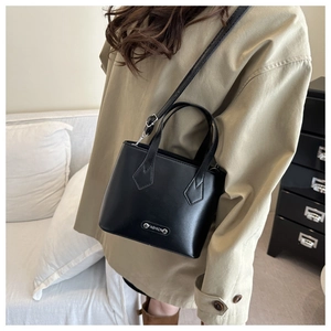 Detail of minimalist black crossbody bag with metal fashion buckle and leather strap