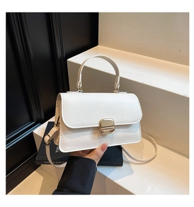 Detail of white minimalist leather handbag with gold metal clasp on a geometric stand