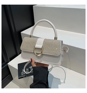 Detail of white leather handbag featuring a sequined flap and golden D-shaped buckle