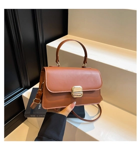 Detailed view of the brown leather mini square bag featuring a gold metal buckle closure