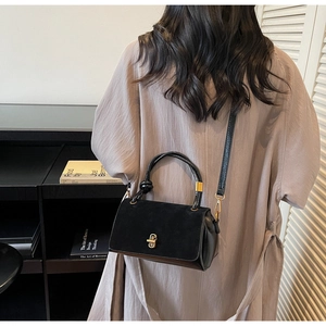 Detail of black suede leather handbag featuring a stylish gold metal lock and knot handle
