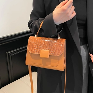 Brown crocodile-effect flap handbag with top handle and crossbody strap on model