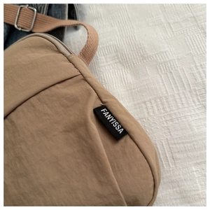 Detail of khaki nylon handbag showing Fanyissa brand label and brown woven shoulder strap